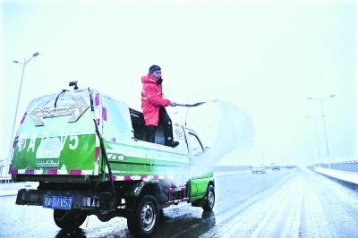  昨日8时30分，洪山城管局机扫队的队员在野芷湖大桥撒盐化雪 我们周超 摄(信息来源：雷霓雰) 
